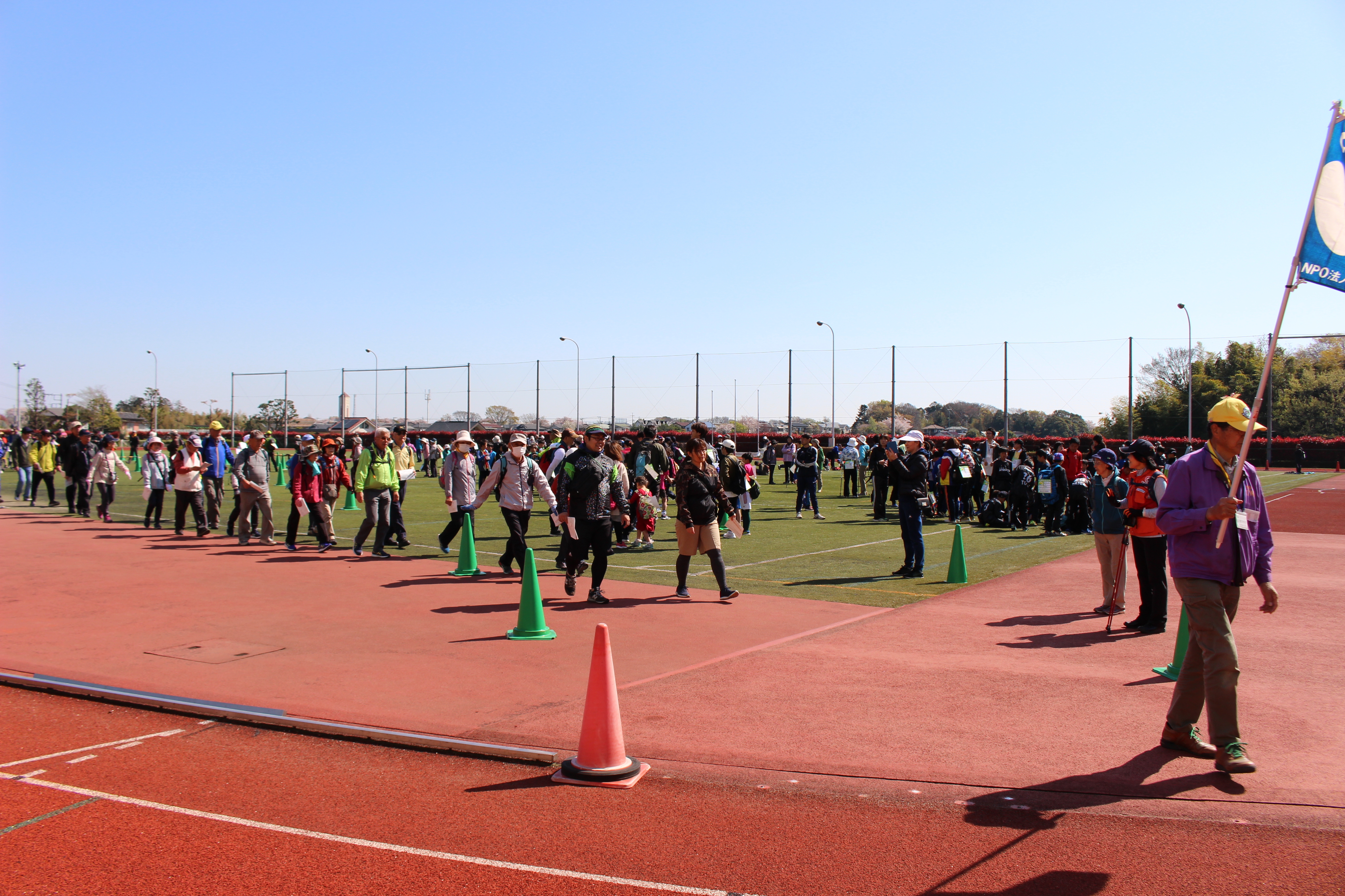 写真：青空のもと、集まった多くの参加者がグラウンドから出発していく様子