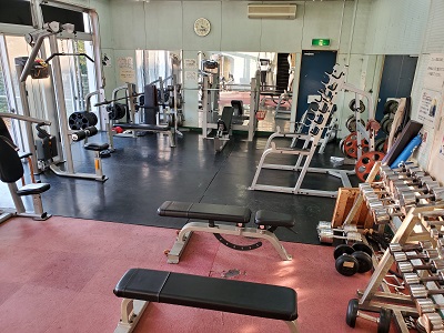 信篤市民体育館トレーニング室内の様子。トレーニングマシンやダンベルが並ぶ。