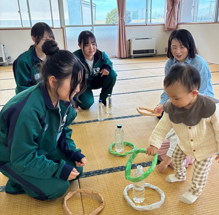 写真:国分高校の生徒が手作りの輪投げで赤ちゃんと遊んでいる様子