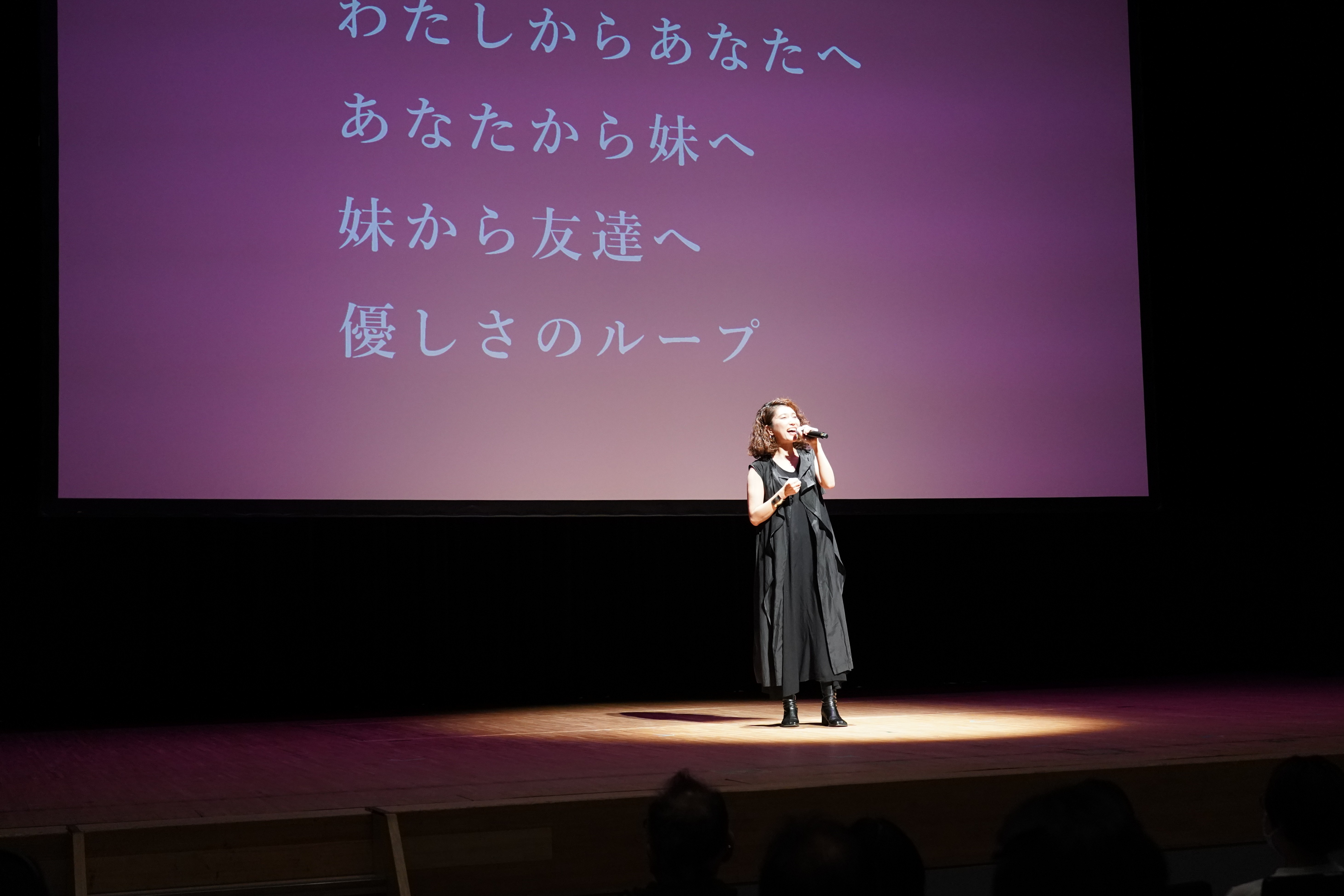 写真：スクリーンの前に上奥まいこ氏がいる様子