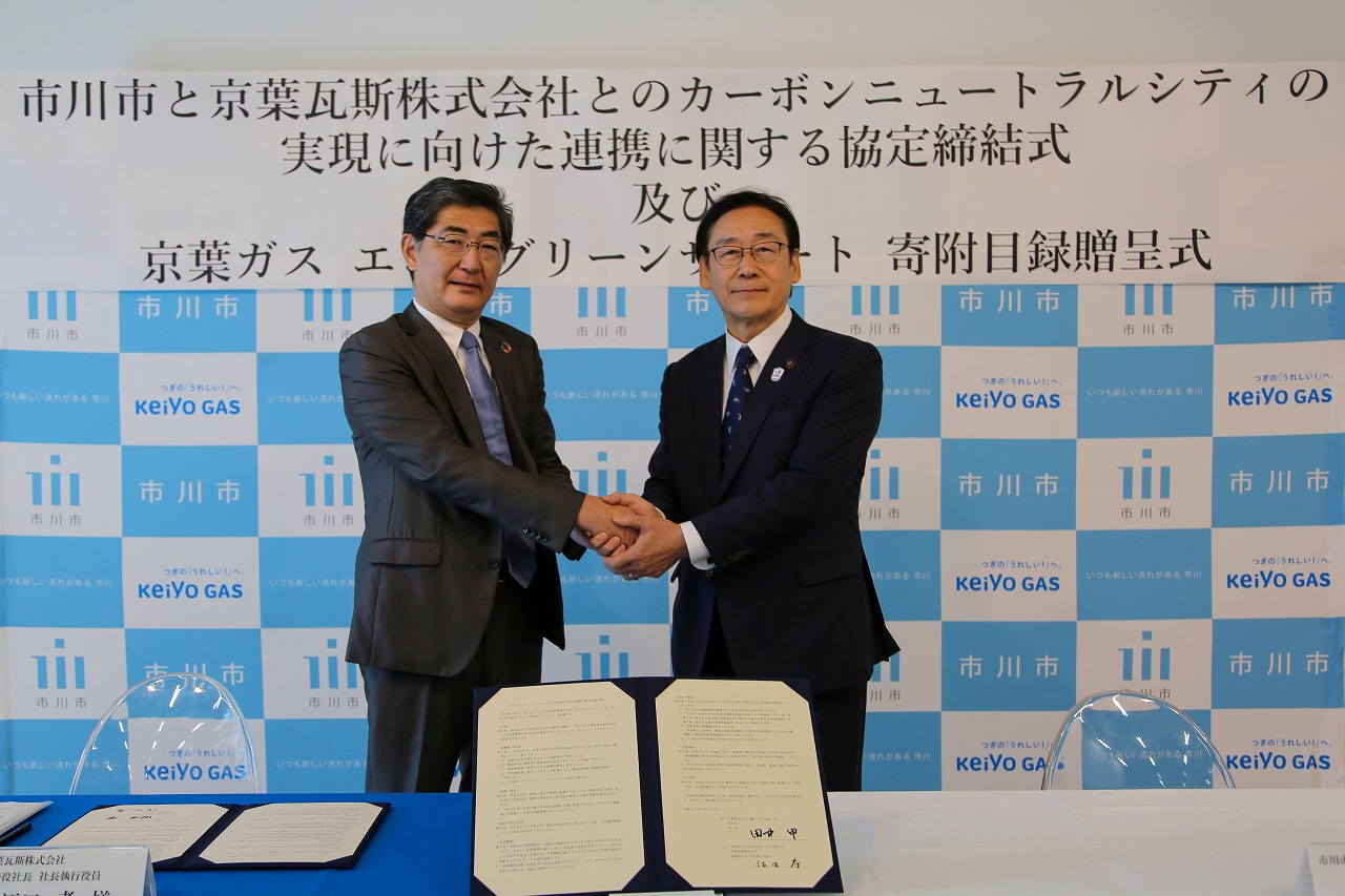 写真：協定締結式の様子。協定書を前に京葉ガス取締役社長と市川市長が固い握手を交わしました。