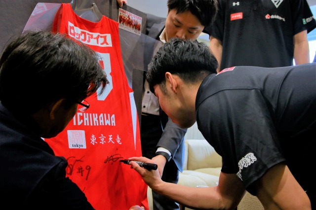 写真：市川市へ寄贈したユニフォームに千葉ジェッツの選手がサインをする様子