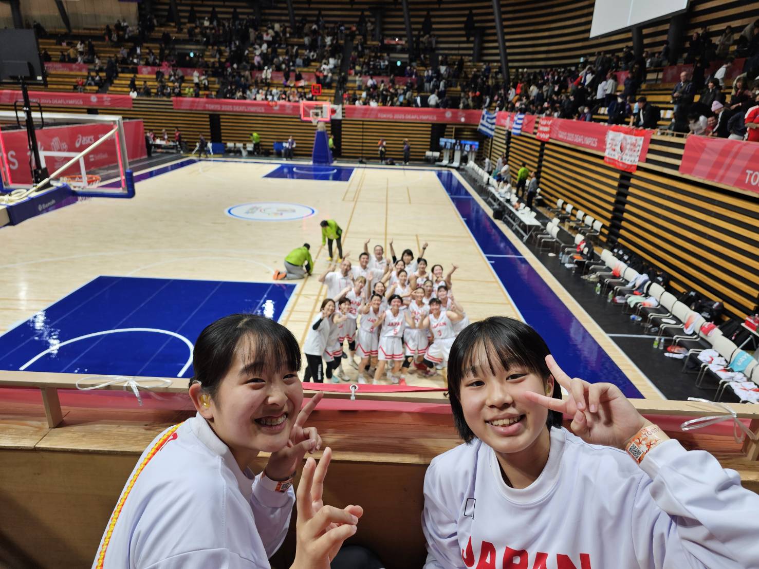 写真:コート上の日本代表チームと観客席の榎本選手