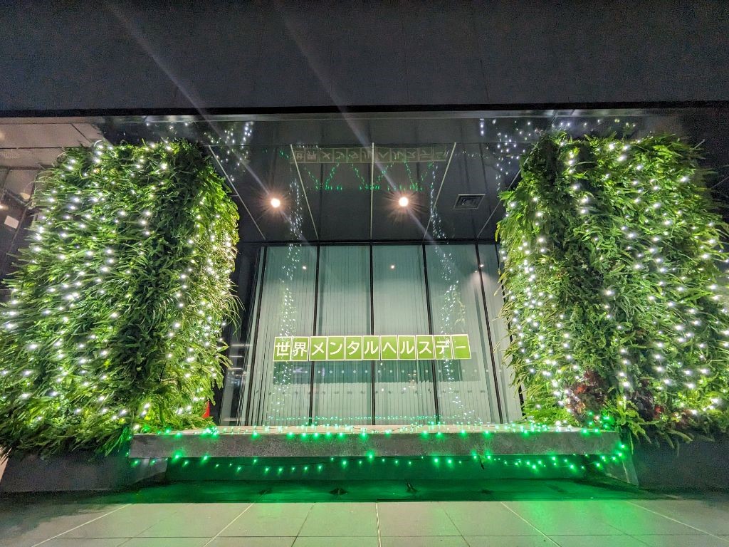 写真:市川市役所第一庁舎入口付近に世界メンタルヘルスデーの掲示を行い、その周りに白と緑の電飾でライトアップを行っている様子、正面からのアングル