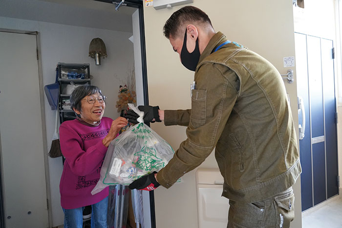 写真：高齢者のお宅を訪問してゴミを受け取る職員