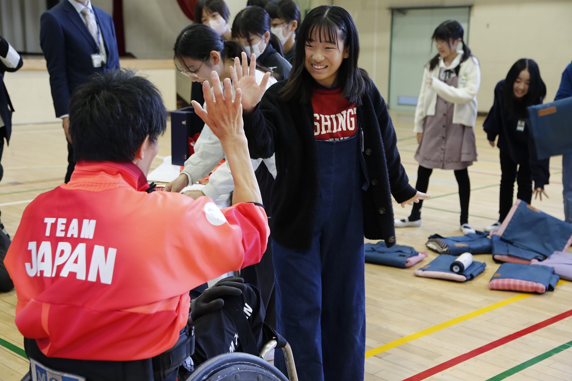 写真：羽賀選手と児童がハイタッチをする様子