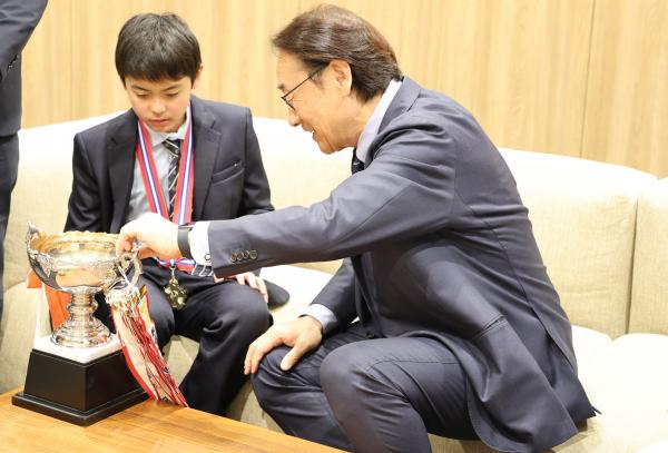写真：トロフィーやメダルを見る田中市長と権瓶珀人選手