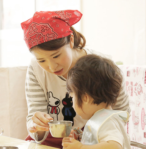 写真:コップの中身を見せる女性とコップの中身をのぞく子ども