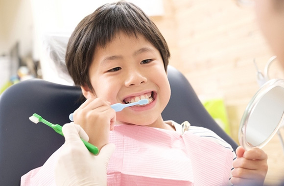写真:歯を磨いている鏡を持った子ども
