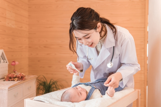 写真:赤ちゃんの体温を測ろうとする女性