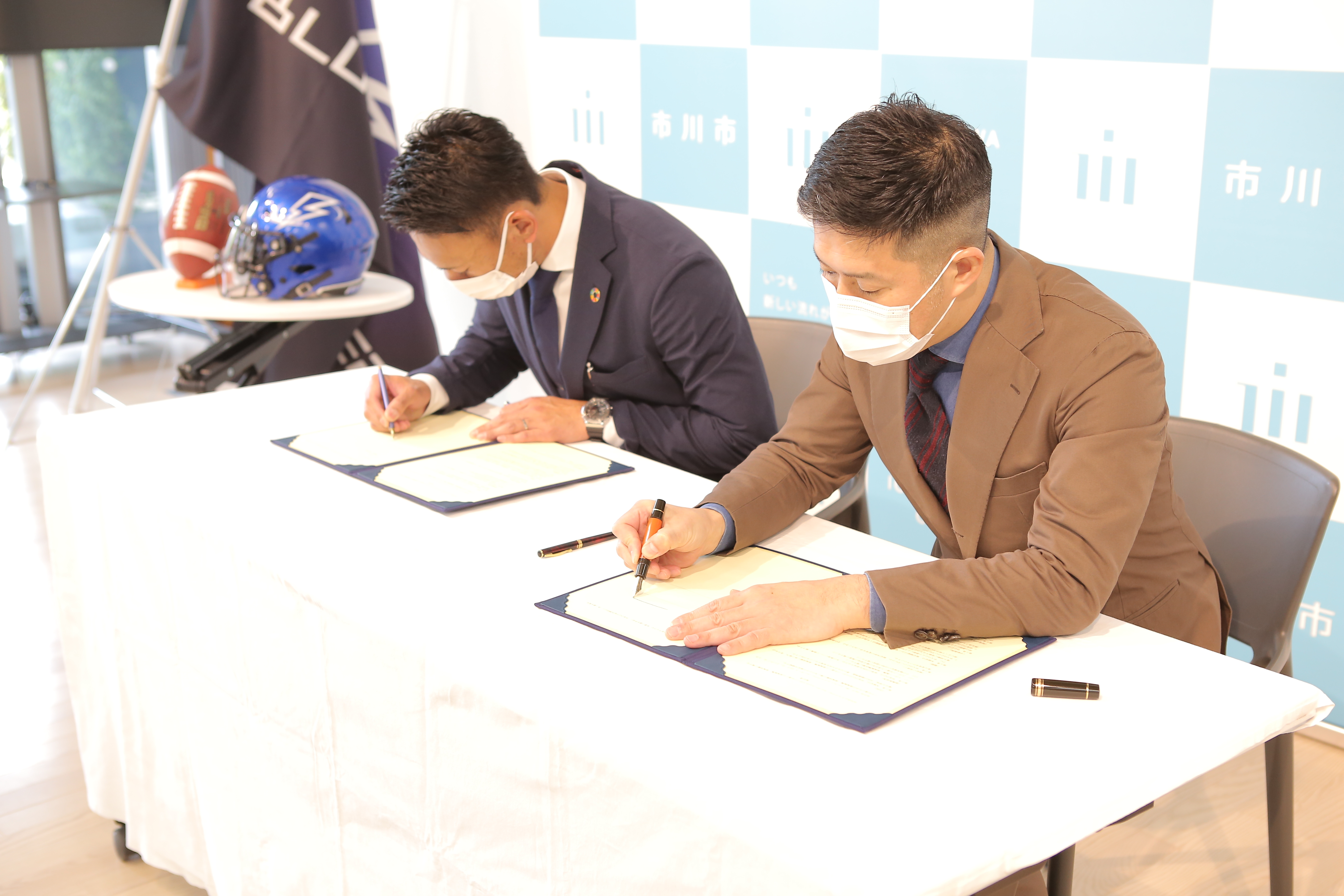 写真：クラブブルーサンダースゼネラルマネージャーと市川市長が協定書に署名している様子