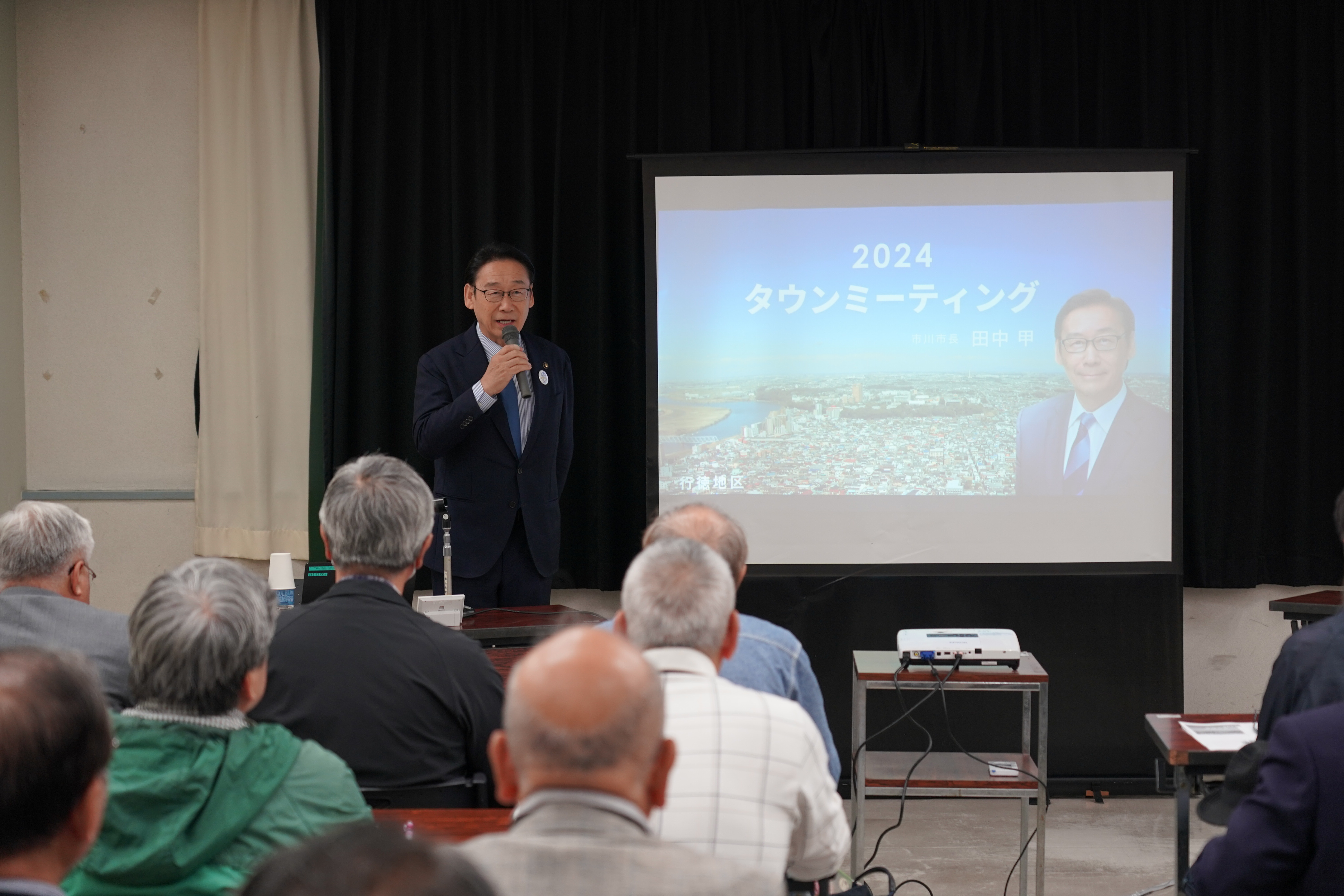 写真：タウンミーティングで田中市長がマイクを握り集まった方に説明する様子