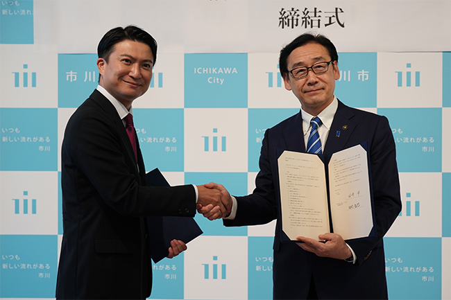 写真：握手する田村代表取締役社長と田中市長